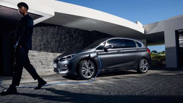 Plug-in-Hybrid BMW 225xe Active Tourer F45 Dreiviertel-Seitenansicht vor Gebäude Plug-in-Hybrid BMW 225xe Active Tourer F45 Dreiviertel-Seitenansicht vor Gebäude mit Model