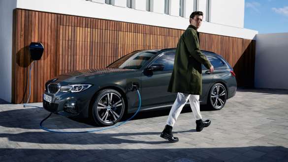 Plug-in-Hybrid BMW 3er Touring 2021 G21 Dreiviertel-Seitenansicht an BMW Wallbox Plug-in-Hybrid BMW 3er Touring 2021 G21 Dreiviertel-Seitenansicht an BMW Wallbox mit Model