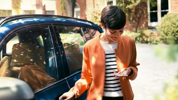 Frau mit Blick auf Smartphone Frau steigt aus BMW mit Blick auf Smartphone