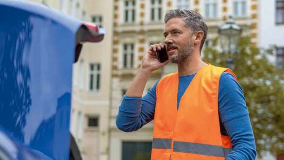 Mann steht an BMW Kofferraum
Mann steht an BMW Kofferraum mit Handy und Warndreieck in den Händen