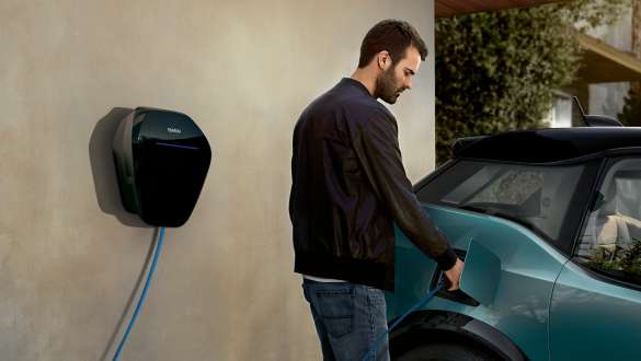 Mann lädt seinen BMW i3 I01 2018 an BMW Wallbox Mann mit BMW Wallbox Ladekabel BMW i3 I01 2018 Blue Ridge Mountain mit Akzent Frozen Grey metallic