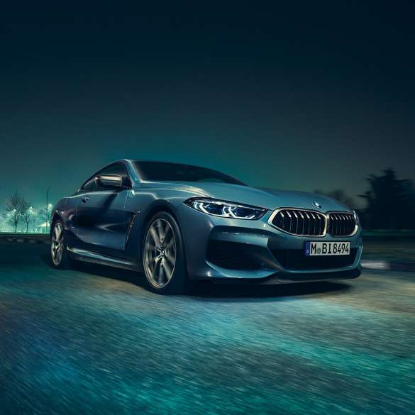 BMW M850i xDrive Coupé, Dreiviertel-Frontansicht links. G15 BMW M850i xDrive Coupé in Barcelona Blau metallic, Dreiviertel-Frontansicht links, fahrend bei Nacht. G15