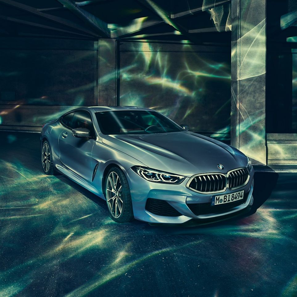 BMW M850i xDrive Coupé, Dreiviertel-Frontansicht links. G15 BMW M850i xDrive Coupé in Barcelona Blau metallic, Dreiviertel-Frontansicht links, stehend vor Gebäude. G15