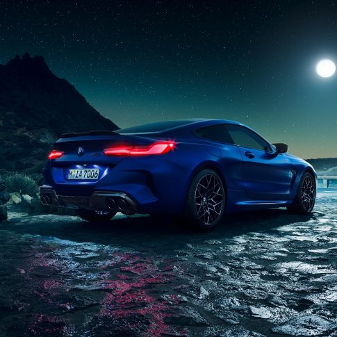 BMW M8 Competition Coupé, Dreiviertel-Heckansicht. F92 BMW M8 Competition Coupé in Marina Bay Blau metallic mit strahlenden LED-Heckleuchten, stehende Dreiviertel-Heckansicht bei Vollmond. F92