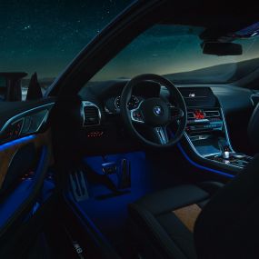 Interieur BMW M8 Competition Coupé. F92 BMW M8 Competition Coupé, Interieur bei Nacht mit M Lederlenkrad und blauem ambienten Licht bei geöffneter Fahrertür. F92