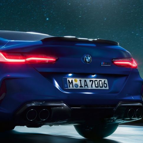 M Diffusor in Carbon Schwarz. F92 BMW M8 Competition Coupé in Marina Bay Blau metallic, Nahaufnahme Heck bei Nacht mit M Diffusor in Carbon Schwarz. F92