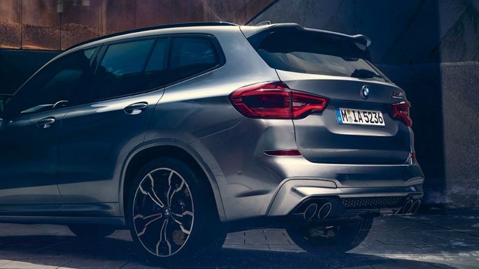 BMW X3 M Competition SUV, seitliche Heckansicht F97. BMW X3 M Competition SUV in Donington Grau metallic, Exterieur, seitliche Heckansicht mit zwei Personen im Vordergrund F97.