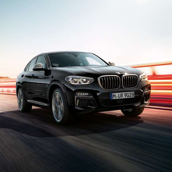 BMW X4 M40i, Dreiviertel-Heckansicht. BMW X4 M40i in Saphierschwarz metallic, fahrend, Exterieur, Dreiviertel-Heckansicht mit Lichtstreifen.