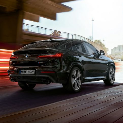 BMW X4 M40i, Dreiviertel-Heckansicht. BMW X4 M40i in Saphierschwarz metallic, Exterieur, Dreiviertel-Heckansicht rechts mit Lichtstreifen.