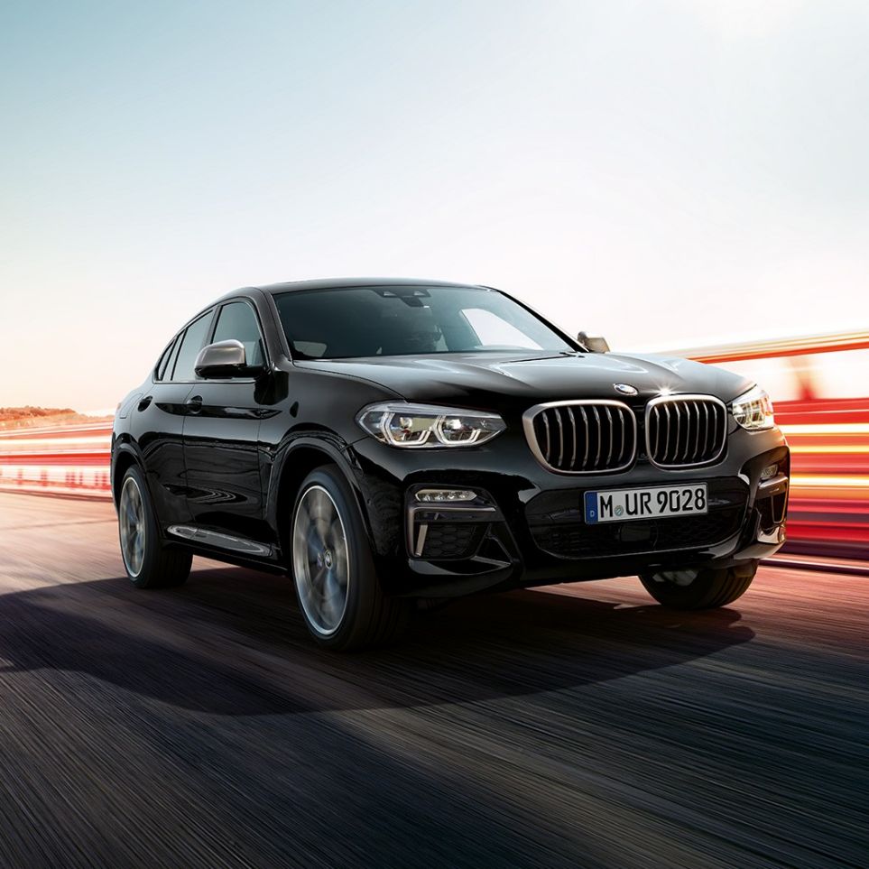 BMW X4 M40i und BMW X4 M40d, Dreiviertel-Frontansicht. BMW X4 M40i und BMW X4 M40d in Saphierschwarz metallic, Exterieur, Dreiviertel-Frontansicht links mit Lichtstreifen.
