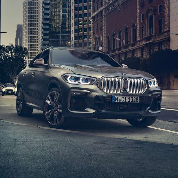 BMW X6 adaptives M Fahrwerk Professional. G06 BMW X6 in Dreiviertel-Front Perspektive vor urbaner Kulisse. G06