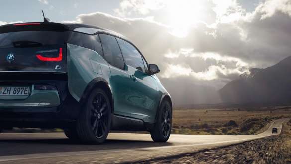 BMW i3 2018 vue de trois quarts arrière roulant sur une route de campagne BMW i3 I01 2018 Jucarobeige avec accent Frozen Grey metallic vue de trois quarts arrière roulant sur une route de campagne