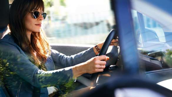 Une femme avec des lunettes de soleil conduit une BMW i3 Une femme avec des lunettes de soleil conduit une BMW i3