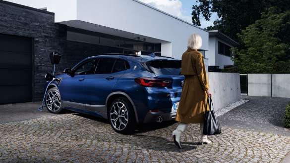 BMW X2 xDrive25e F39 hybride rechargeable, vue de trois quarts arrière branchée à une borne BMW X2 xDrive25e F39 hybride rechargeable, vue de trois quarts arrière branchée à une borne avec modèle