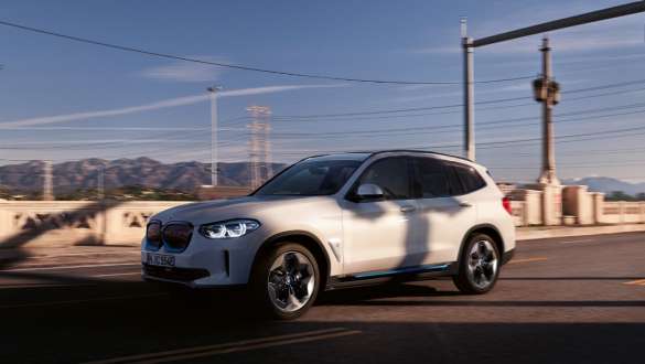 Suspension M adaptative BMW iX3 SUV électrique G08 en mouvement sur la route Suspension M adaptative BMW iX3 SUV électrique G08 2020 en Mineralweiß metallic, vue de trois quarts avant en mouvement sur la route