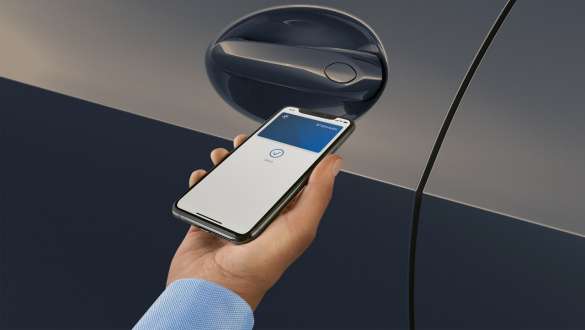 Accès confort BMW X7 G07 LCI – main tenant un smartphone devant la poignée de porte Accès confort BMW X7 G07 LCI – main tenant un smartphone devant la poignée de porte