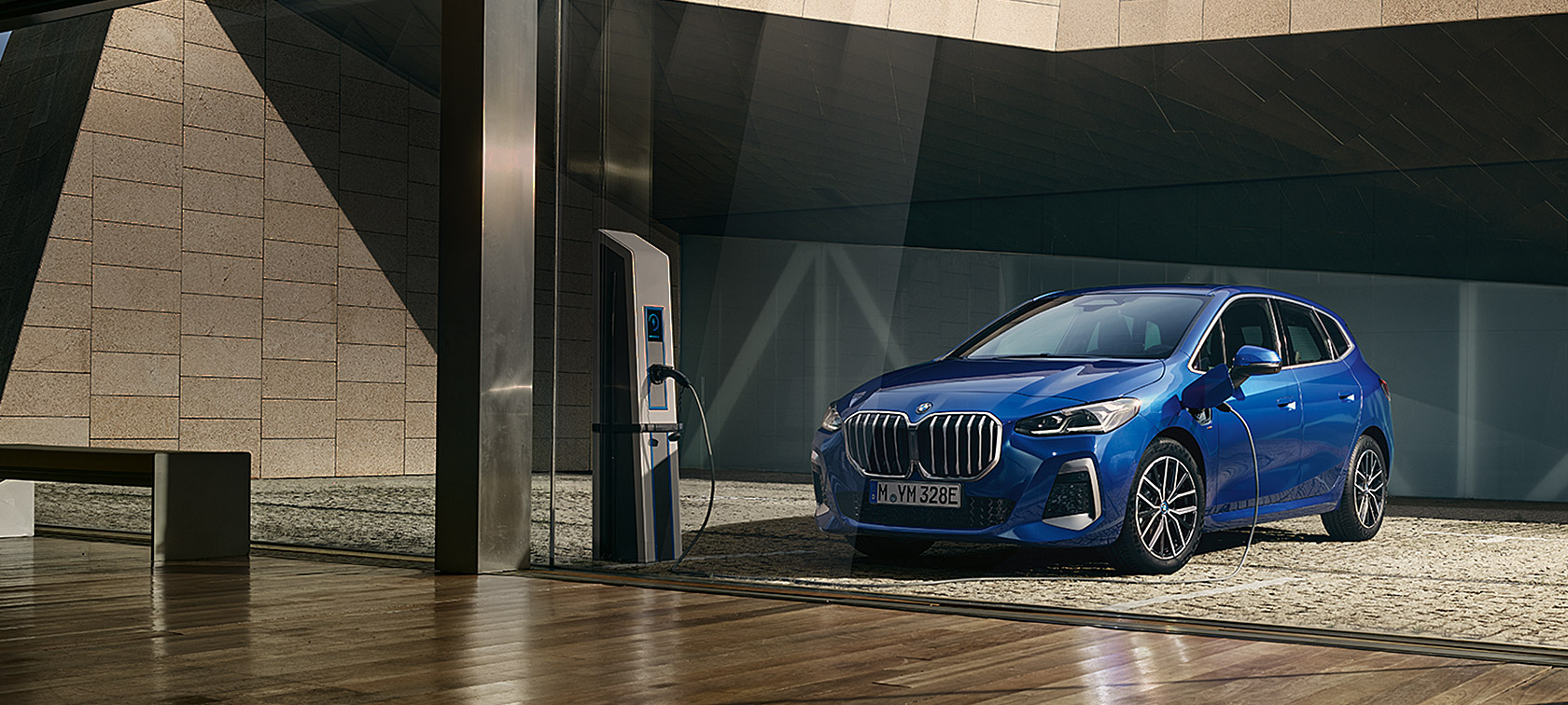 BMW 2er Active Tourer 230e Plug-in-Hybrid U06 2021 M Portimao Blau metallic Dreiviertel-Frontansicht an der Ladesäule
