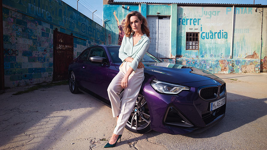 Femme appuy&eacute;e &agrave; la BMW S&eacute;rie&nbsp;2&nbsp;Coup&eacute;&nbsp;G42&nbsp;vue de trois quarts avant.