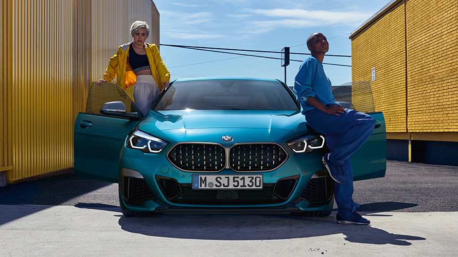 BMW 2er Gran Coupé F44, Frontansicht BMW 2er Gran Coupé F44 Snapper Rocks Blau metallic, Frontansicht mit geöffneten Türen und zwei Personen am Fahrzeug