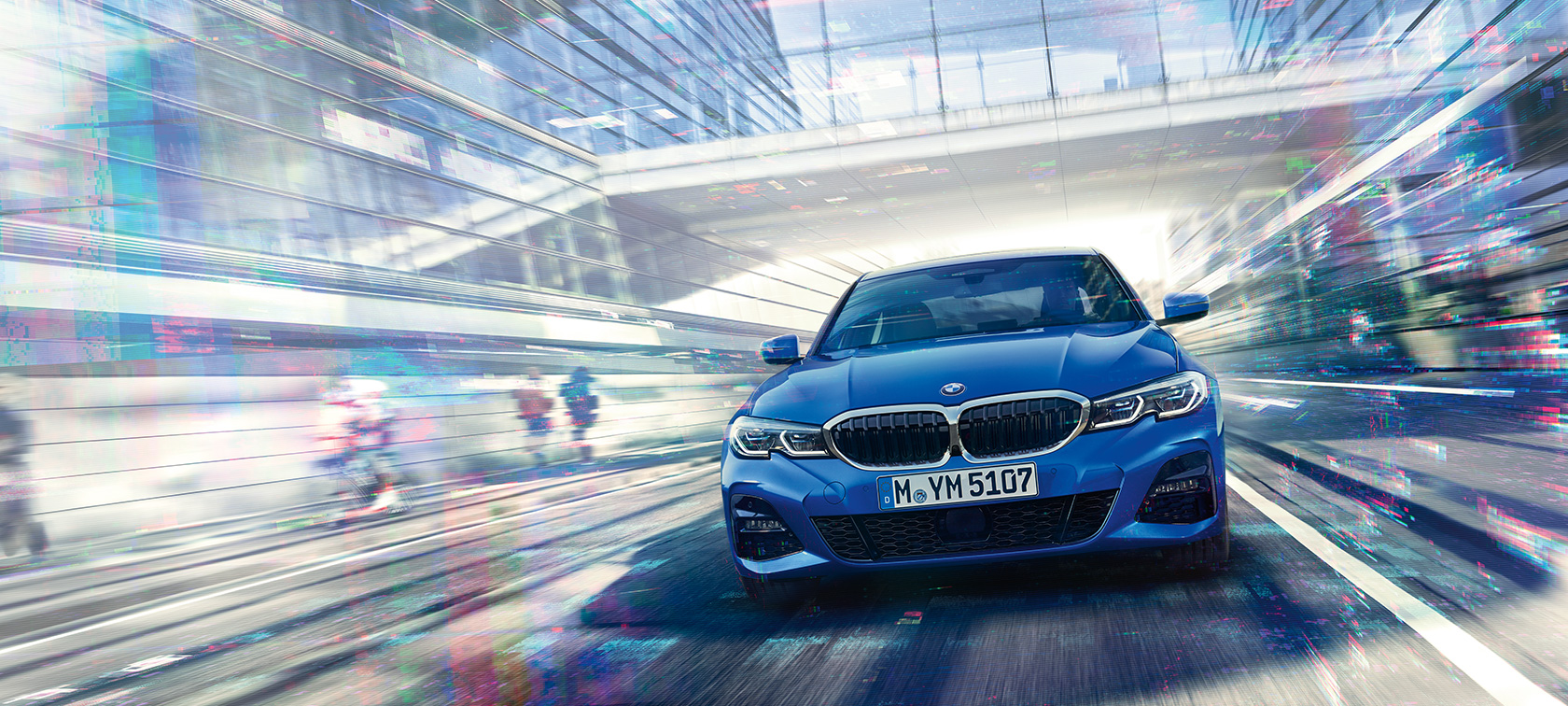 BMW Série 3 Berline, vue de face G20. Vue de face de la BMW Série 3 Berline en mouvement de jour sous des immeubles de verre G20.