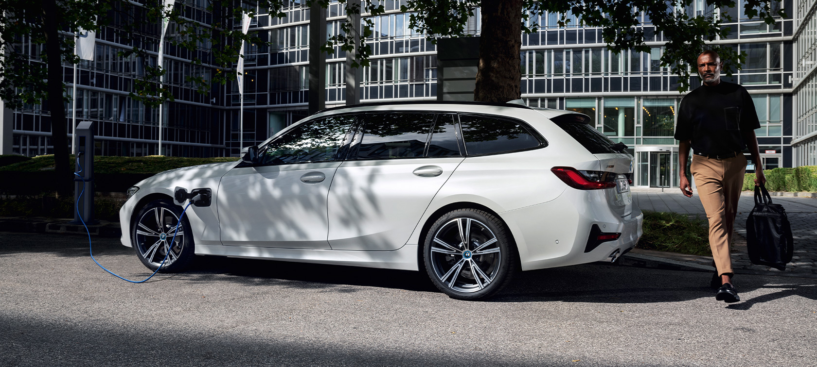 Plug-in-Hybrid BMW 3er Touring 2021 G21 Dreiviertel-Seitenansicht ladend Plug-in-Hybrid BMW 3er Touring 2021 G21 Dreiviertel-Seitenansicht ladend mit Model