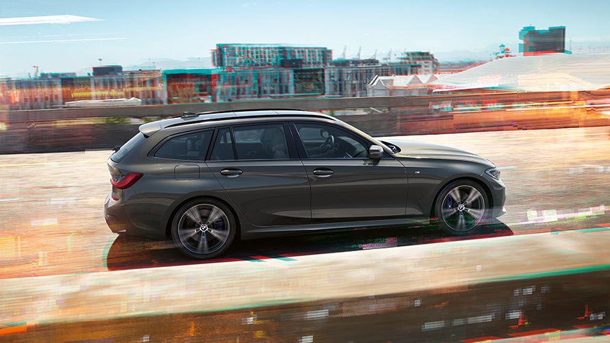 BMW 3er Touring, seitliche Aufnahme bei der Fahrt auf Straße vor urbaner Kulisse