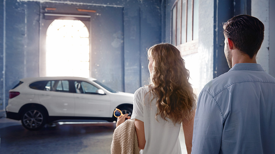 BMW Financial Services pour la BMW Série 4 Cabrio. Couple se tenant devant une BMW X blanche dans un hall, BMW Financial Services