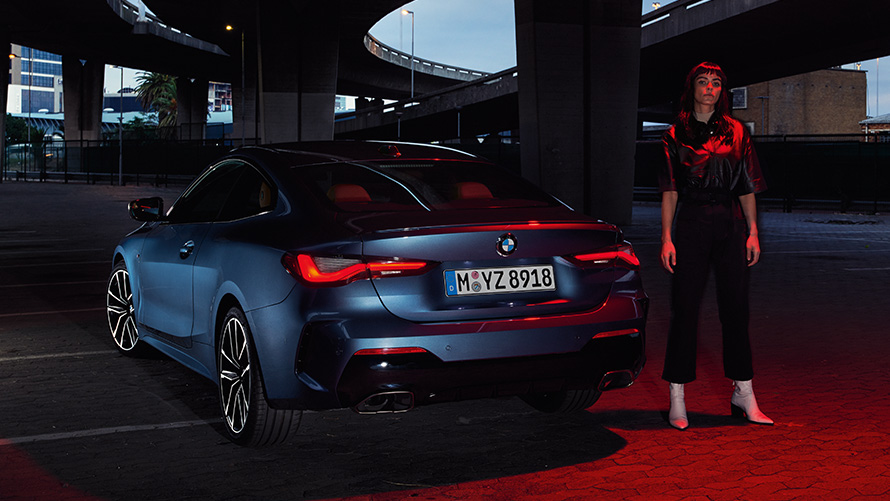 BMW 4 Series Coupé (G22), Artic Race Blue metallic, rear view with person BMW 4er Coupé (G22), Artic Race Blue metallic, Heckansicht mit Person