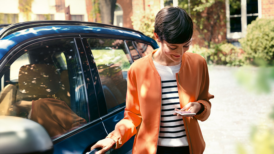 BMW Service Frau mit Smartphone an der Tür ihres BMW BMW Service Frau mit Smartphone an der Tür ihres BMW