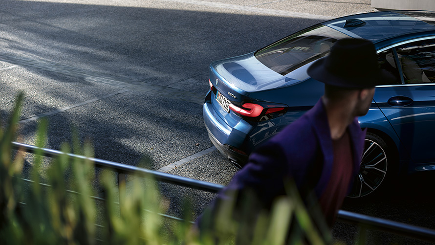 BMW Série 5 Berline G30 restylage 2020, un homme se tient derrière la BMW stationnée 