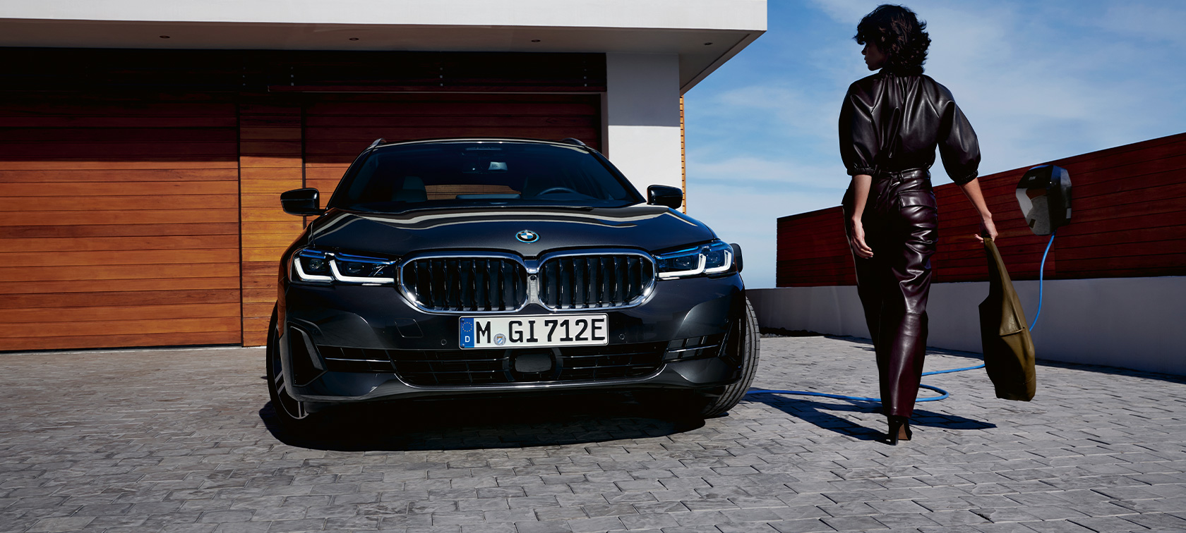 BMW Série 5 Touring hybride rechargeable 2021 G31, vue avant branchée à une borne de recharge BMW Série 5 Touring hybride rechargeable 2021 G31, vue avant branchée à une borne de recharge avec modèle
