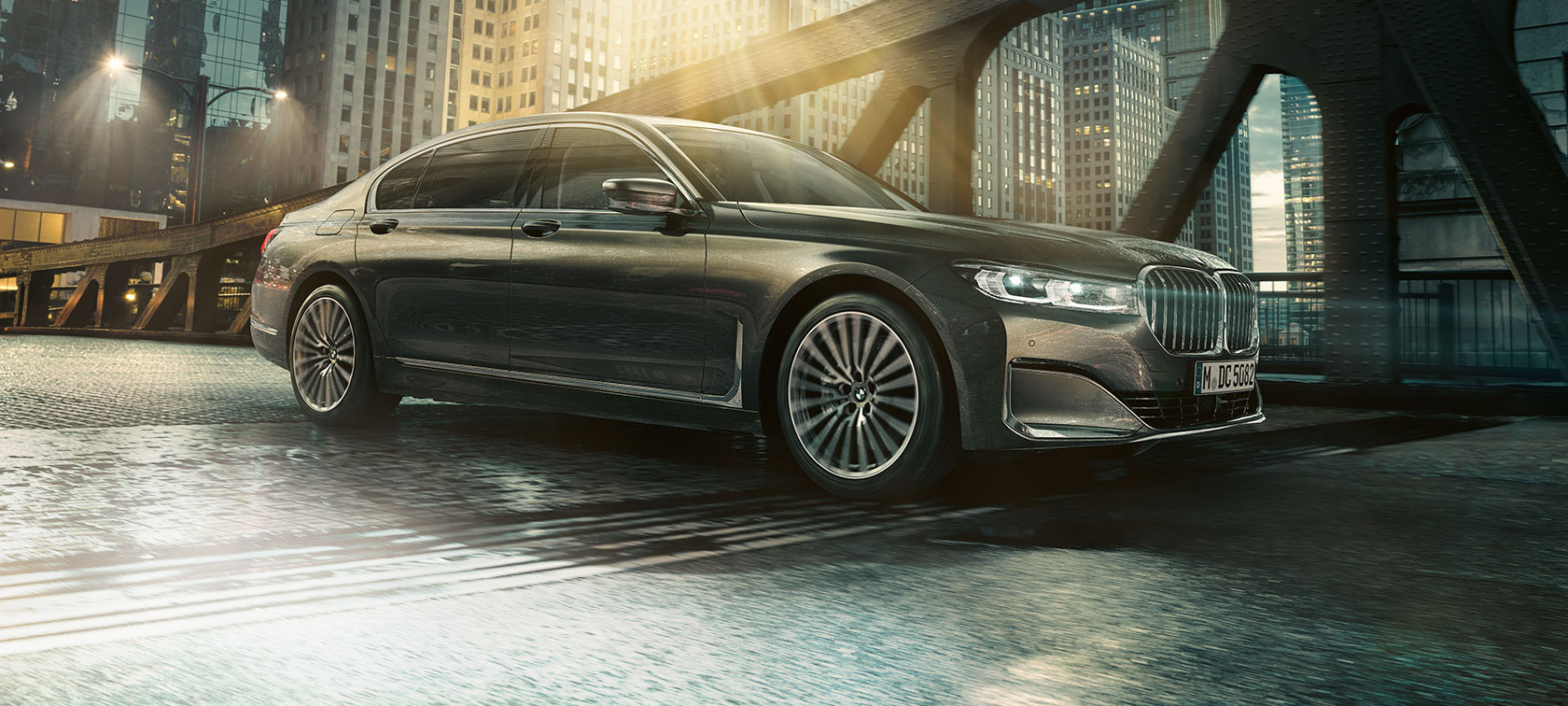 BMW Série 7 Berline, vue latérale G11 Vue latérale de la BMW Série 7 Berline avec portière ouverte devant un hôtel éclairé G11