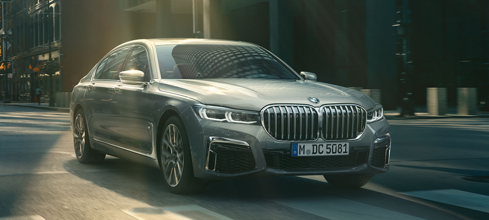Vue de trois quarts avant d’une BMW Série 7 Berline grise en mouvement G11 Vue de trois quarts avant d’une BMW Série 7 Berline grise roulant dans un décor urbain G11