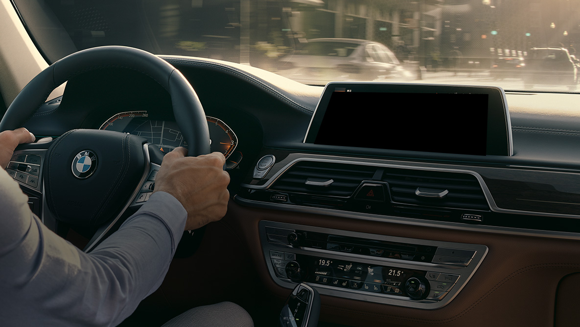 BMW Intelligent Personal Assistant G11 BMW Intelligent Personal Assistant: Mann fährt in BMW, Nahaufnahme des Live Cockpit Professional G11