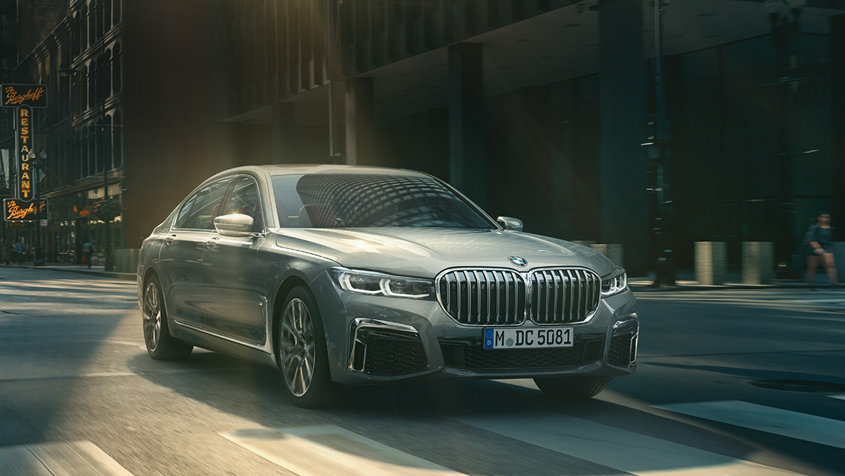 BMW 7er Driving Assistant Pack Professional G11 Driving Assistant Pack Professional: Dreiviertelfrontaufnahme des BMW 7er fahrend vor urbaner Kulisse G11