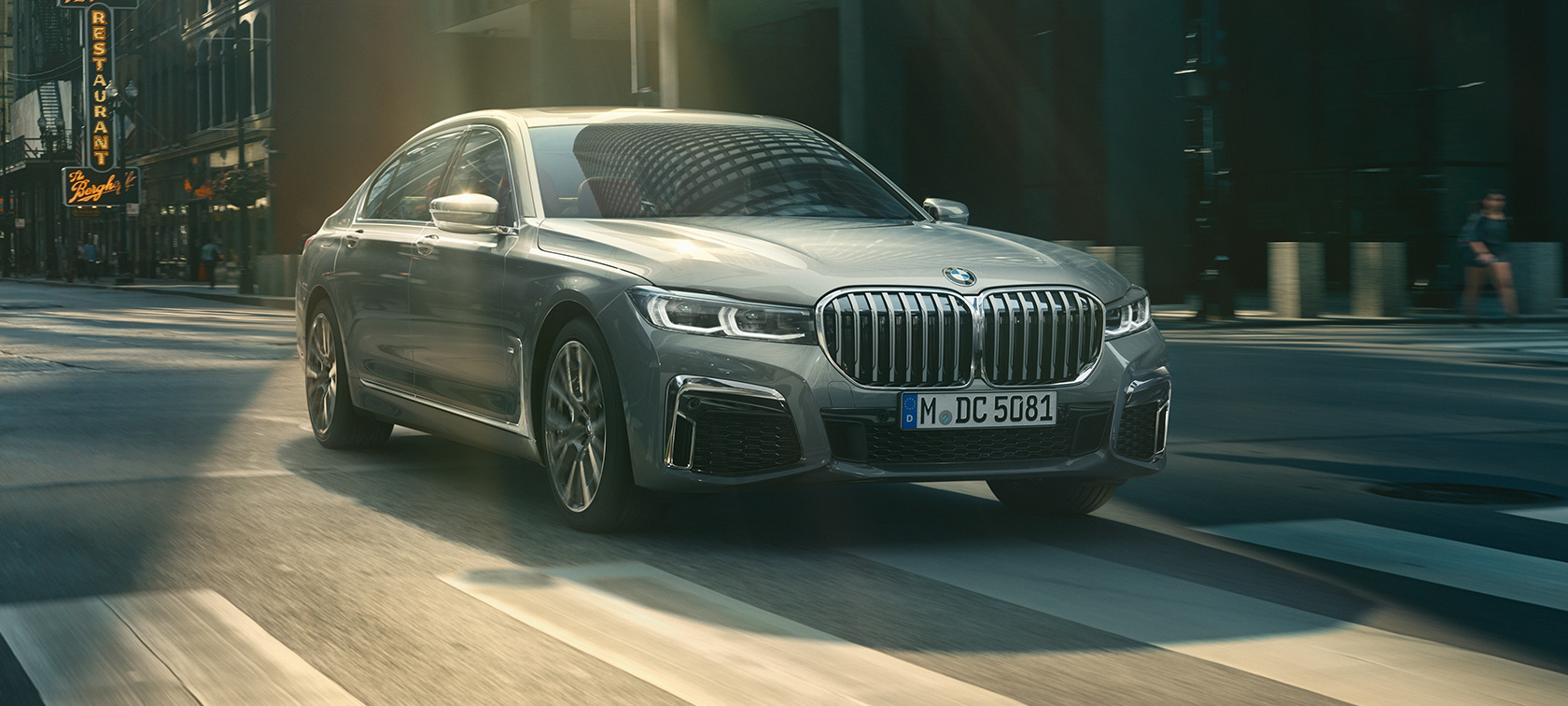 Vue de trois quarts avant d’une BMW Série 7 Berline grise en mouvement G11 Vue de trois quarts avant d’une BMW Série 7 Berline grise roulant dans un décor urbain G11