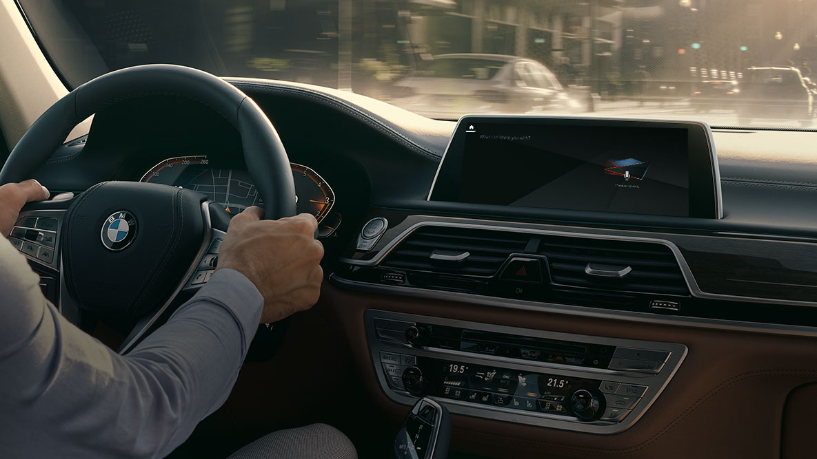 BMW Intelligent Personal Assistant G11 BMW Intelligent Personal Assistant : homme en train de conduire une BMW, vue en gros plan du Live Cockpit Professional G11