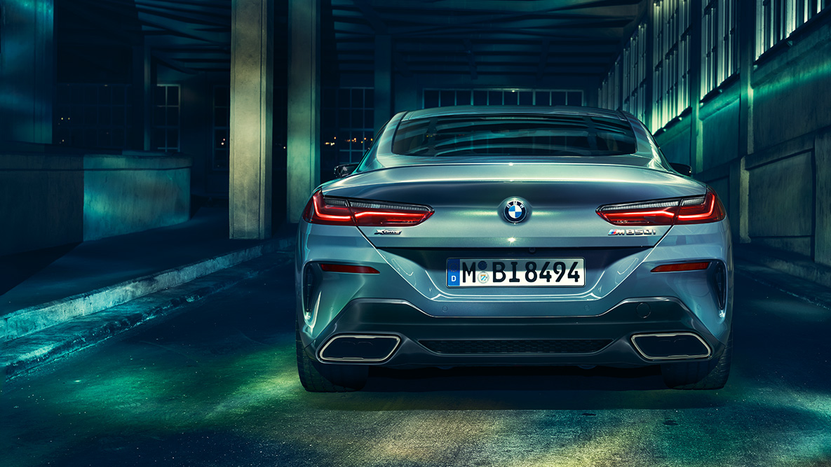 BMW 8er Coupé, Heckansicht. Heckansicht des BMW 8er Coupé in der Nacht vor urbaner Kulisse.
