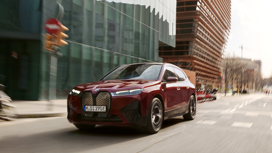 BMW iX i20 elektrischer SUV BMW iX xDrive50 Fahrerassistenz BMW iX i20 2021 elektrischer SUV BMW iX xDrive50 Aventurinrot fahrend in urbaner Umgebung