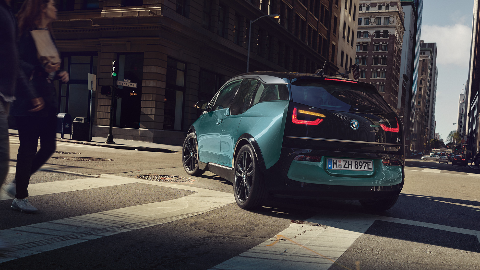 BMW i3 2018 Dreiviertel-Heckansicht fahrend I01 BMW i3 I01 2018 Jucarobeige mit Akzent Frozen Grey metallic Dreiviertel-Heckansicht fahrend in urbaner Kulisse