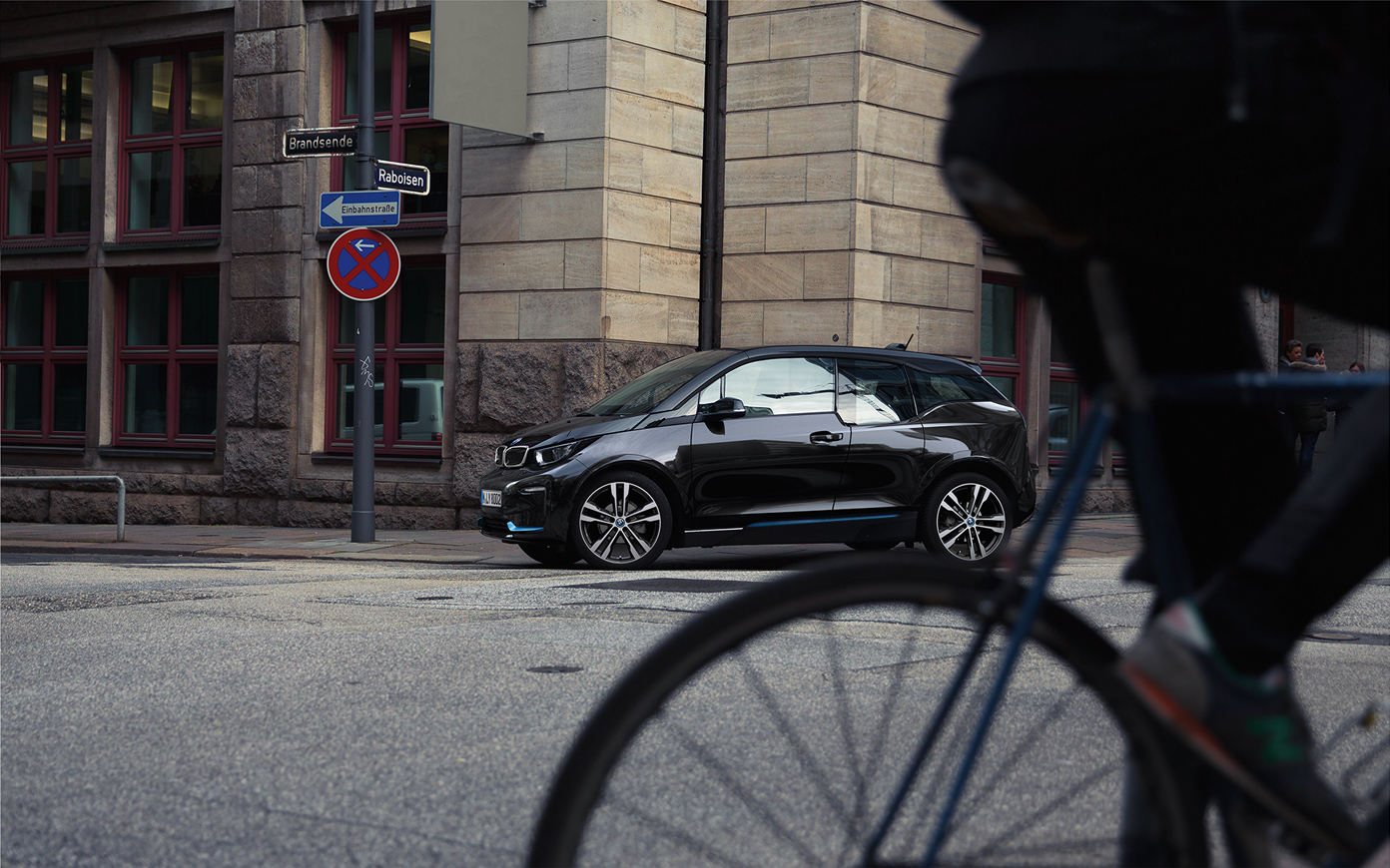 BMW i3s voiture électrique I01 2018, vue de profil BMW i3s I01 voiture électrique 2018 en Fluid Black avec accent BMWi Blau vue de profil en mouvement dans un décor urbain