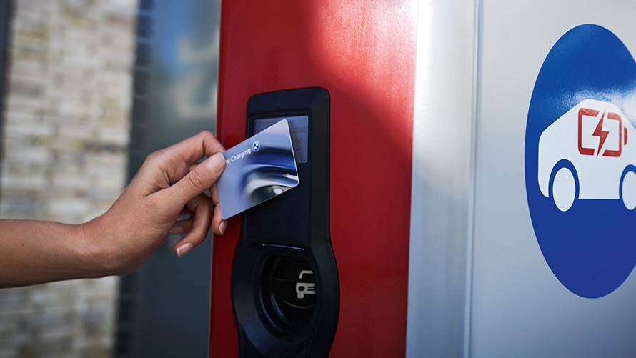 La personne tient la BMW Charging Card à côté d’une borne de recharge publique La personne tient la BMW Charging Card à côté d’une borne de recharge publique