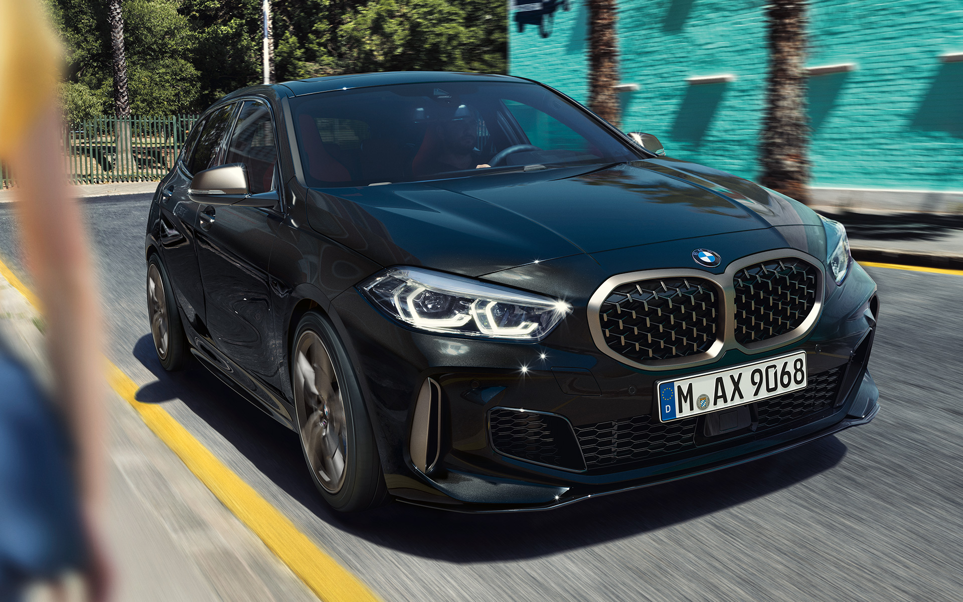 BMW M135i xDrive (F40) in Saphirschwarz metallic, Dreiviertel-Frontansicht fahrend