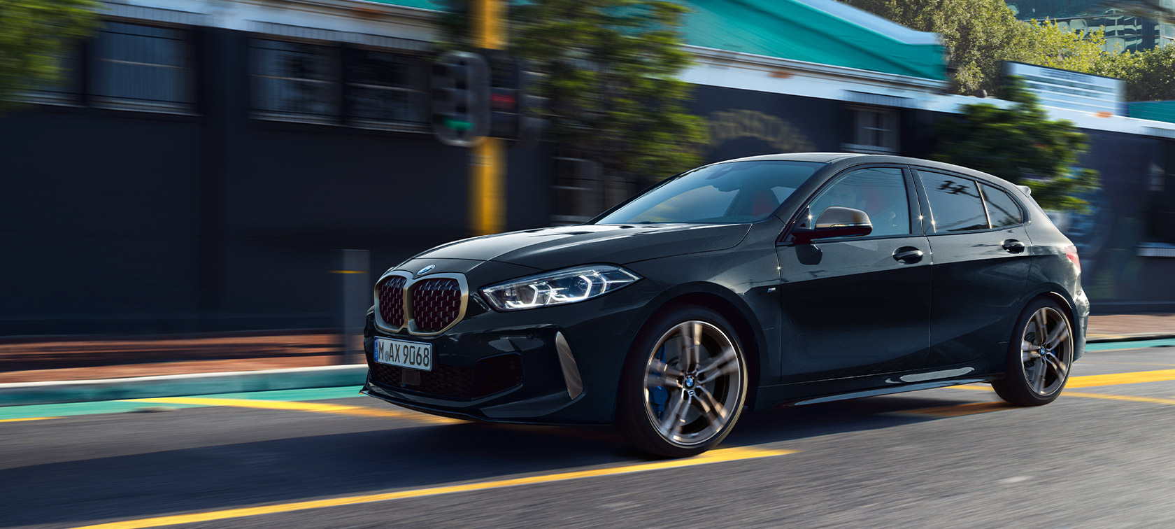 BMW 1er M135i xDrive (F40) in Saphirschwarz metallic Fahrendes Auto in urbaner Umgebung