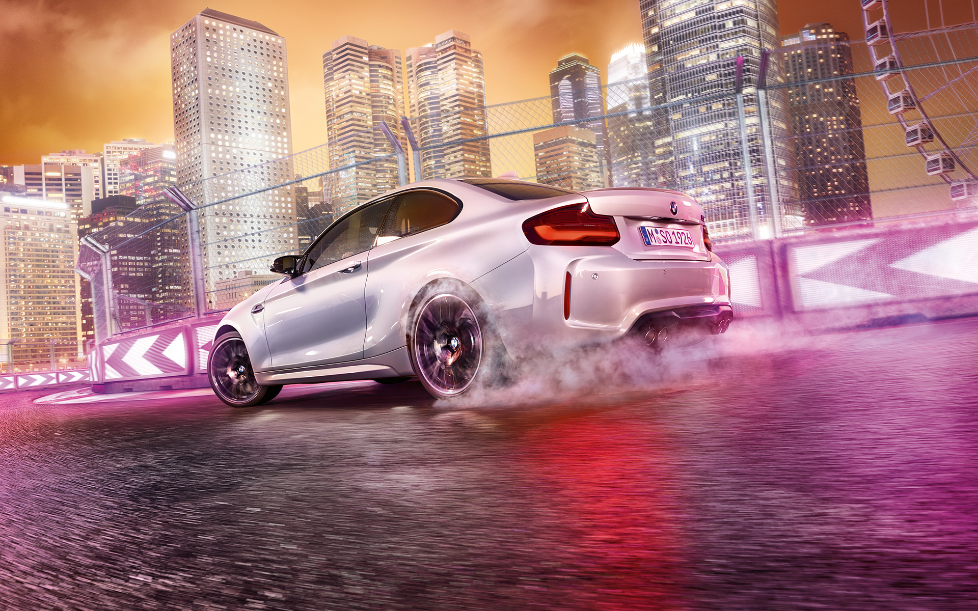 La BMW M2 Competition accélère Une BMW M2 Competition blanche driftant sur le circuit de course, devant une skyline nocturne.