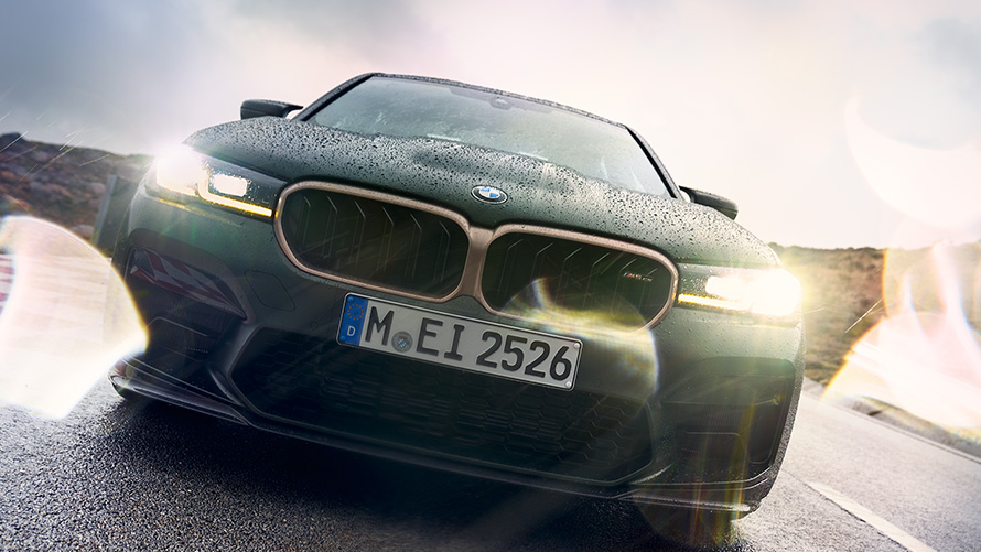 BMW M5 CS F90 2021 Frozen Deep Green metallic Frontansicht mit eingeschaltenen Scheinwerfern