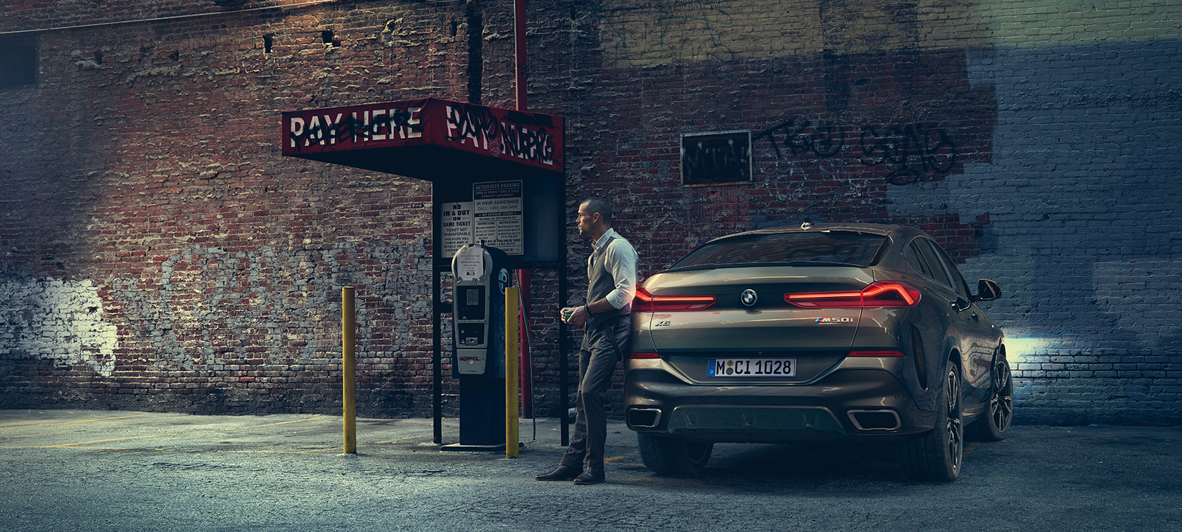 Heck des BMW X6 M50i. Mann lehnt am Heck des BMW X6 M50i.