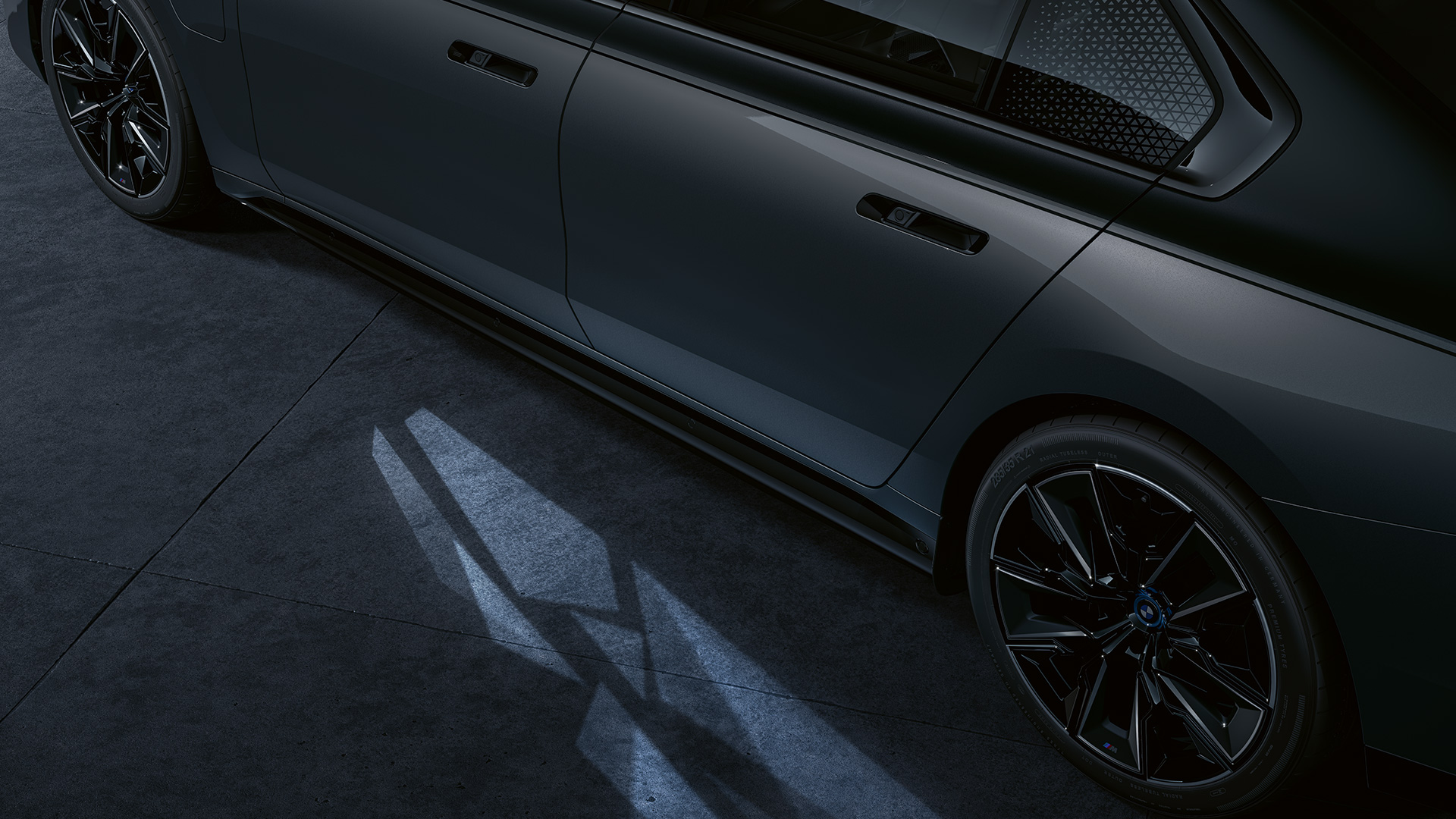 Concept d’éclairage BMW M760e xDrive Berline G70 Concept d'éclairage BMW M760e xDrive Berline G70 teinte bi-ton Saphirschwarz metallic BMW Individual Dravitgrau metallic vue en gros plan latérale avec Welcome Light Carpet activé