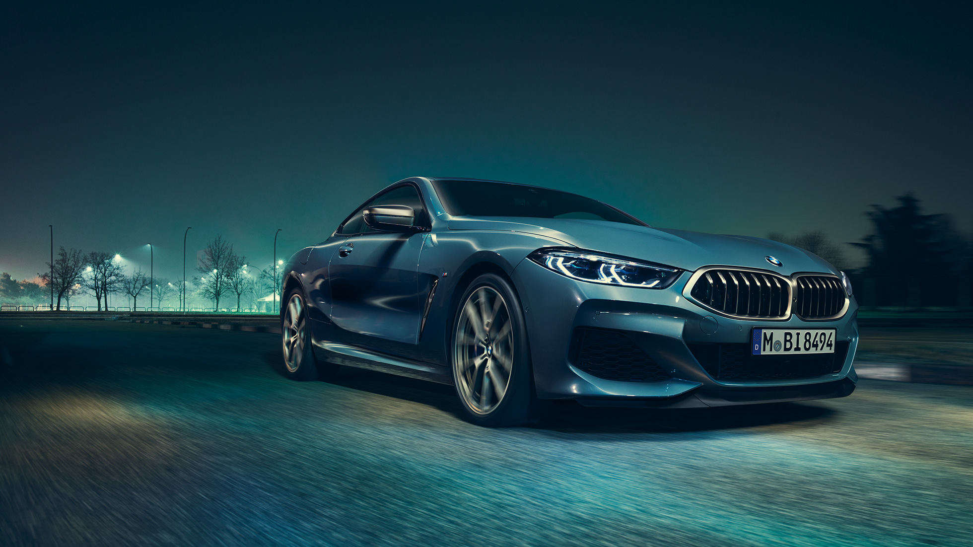 BMW M850i xDrive Coupé, Dreiviertel-Frontansicht links. G15 BMW M850i xDrive Coupé in Barcelona Blau metallic, Dreiviertel-Frontansicht links, fahrend bei Nacht. G15