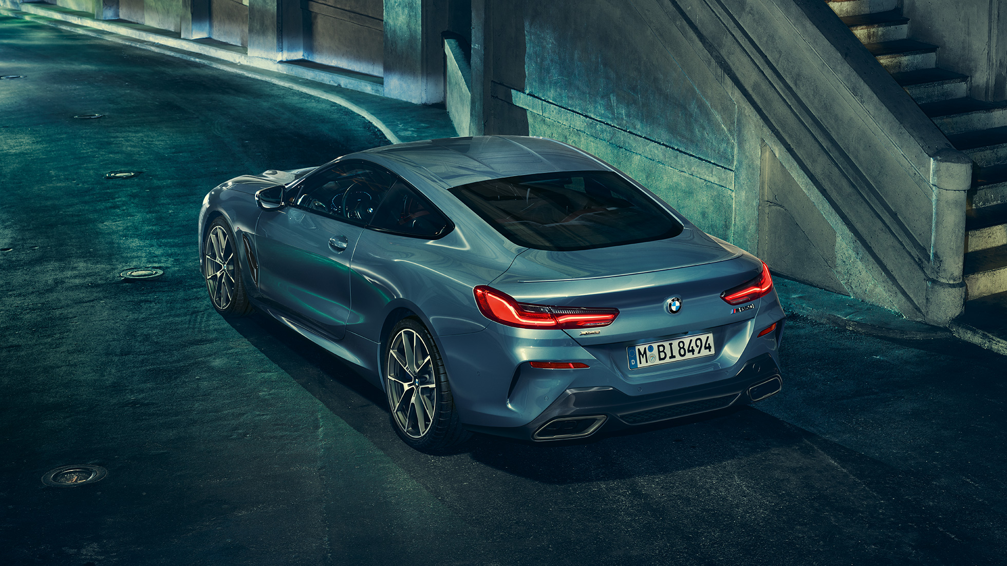 BMW M850i xDrive Coupé, Dreiviertel-Heckansicht links. G15 BMW M850i xDrive Coupé in Barcelona Blau metallic, Dreiviertel-Heckansicht links, stehend bei Nacht. G15